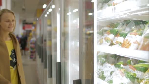 Woman taking frozen product in the shop fridge