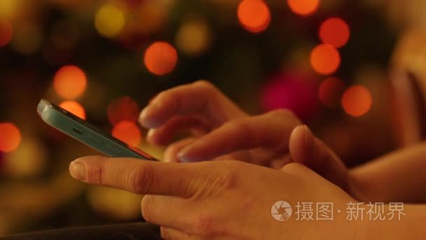 Woman Hands with Smartphone by Christmas Tree