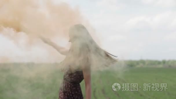 幸福的年轻女人，黑裙与印花开心户外绿色领域。丽质的姑娘用橙色纺纱和笑。中间的镜头视频