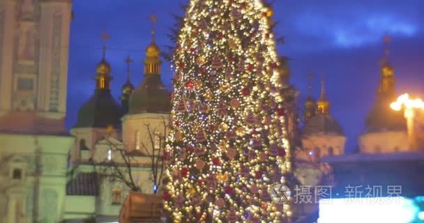 人走在照明的枞树闪亮之星顶级新年树上装饰着灯花环的电视屏幕基辅教会视频金色穹顶