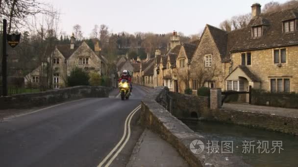 在英格兰老村庄由驾驶的摩托车