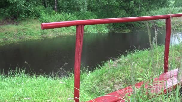 little red bridge and heavy rain drops fall on pond lake water. 