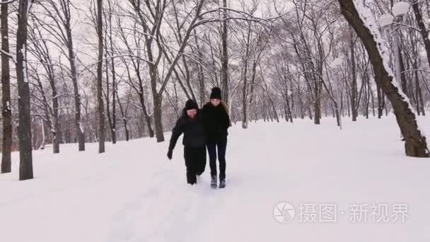 冬天的乐趣-夫妻散步在冰雪覆盖的路和笑