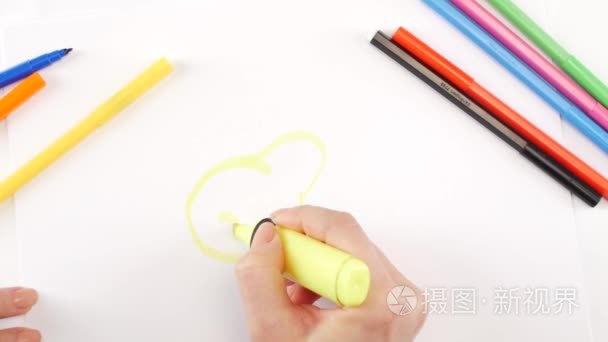 Woman drawing the pear using yellow felt-tip pen on white paper 