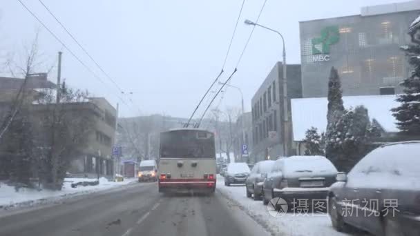 无轨电车开车穿过城市街道在暴风雪中落在冬天。4 k