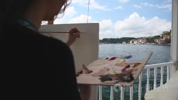 女艺术家用画笔海边绘画