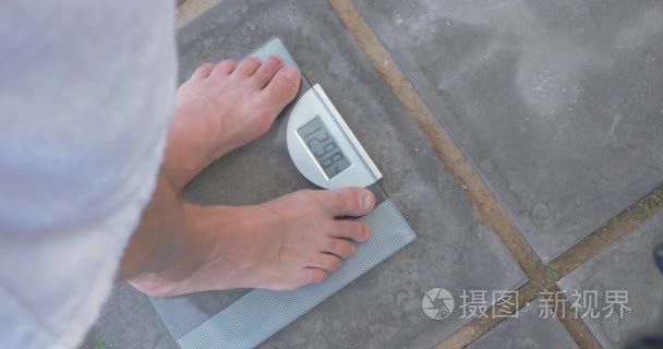 男人浴室磅秤上称自己