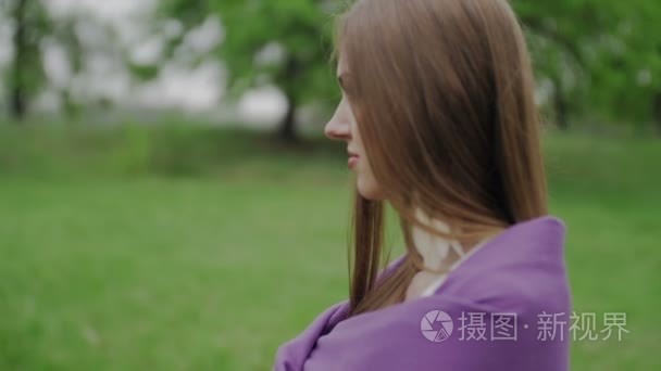 漂亮的女孩站在公园的紫色披风视频