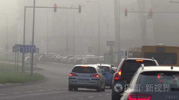 车停在道路交叉口与红色交通灯在厚厚的烟雾。4 k