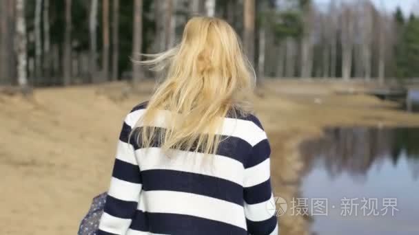 一个女孩走沿湖岸的肖像视频