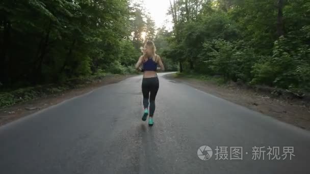 运动女孩跑在林中之路。户外健身。用替身拍摄