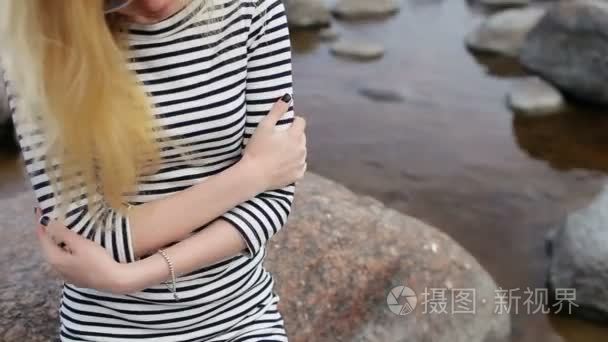 女孩穿着坐在海滩上的岩石温暖视频