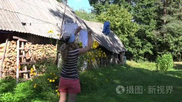 贫穷的国家女人女孩挂洗衣毛巾上农村房子院子里晾衣绳字符串。4 k