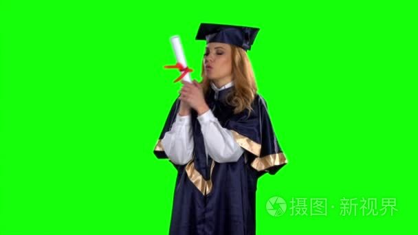 Graduate holding a diploma and kisses him. Green screen. Slow mo