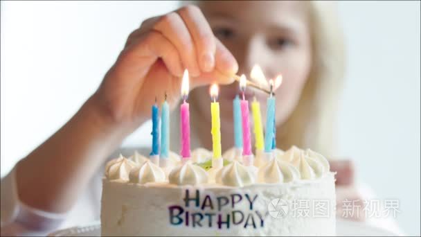 年轻女子照明蜡烛的生日蛋糕上视频