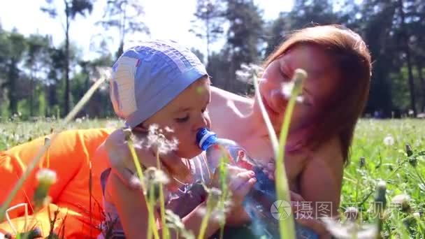 母亲和孩子的饮用水在草地上视频