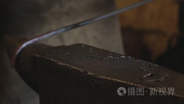铁匠在锤击铁砧上弯曲的金属杆视频
