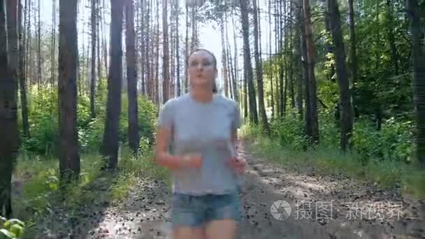 赛跑者女人在公园户外锻炼健身跟踪器可穿戴式技术女孩在树林里露天户外玩体育健康的生活方式，慢跑自然树听跑跑步视频