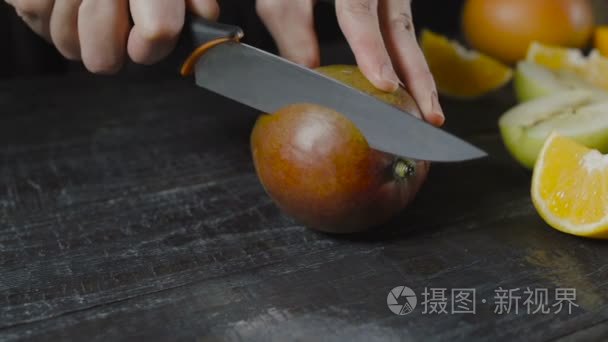 厨师切芒果黑木制的桌子上