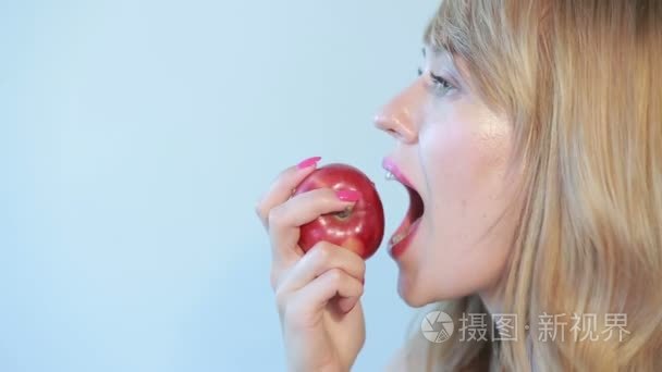 漂亮的女孩吃红苹果蓝