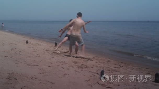 两个家伙在海边沙滩上玩耍迷你足球