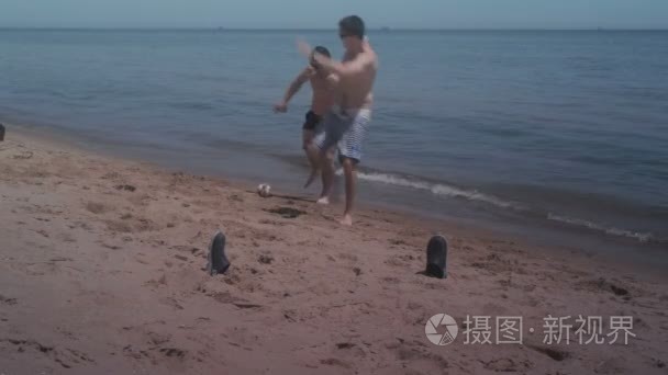 两个家伙在海边沙滩上玩耍迷你足球