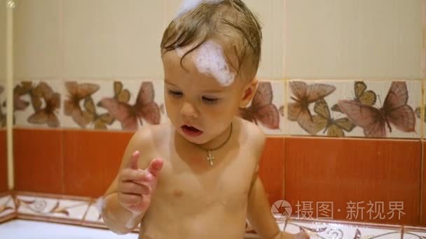 一个孩子玩肥皂泡泡在浴室里