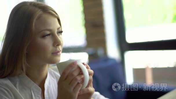 Young thoughtful beautiful woman holding coffee cup and looking 