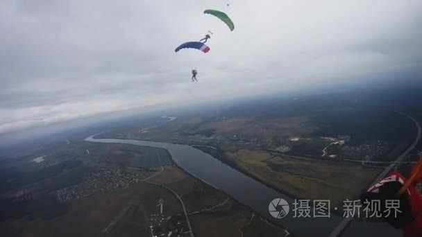 跳伞者在天空中飞过绿色的田野。五颜六色的降落伞。一个极端。集团视频