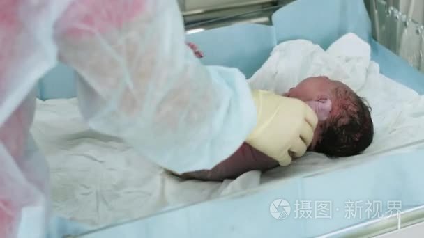 护士检验反射的新生儿哭闹的婴儿，在妇产科医院。用听诊器听心