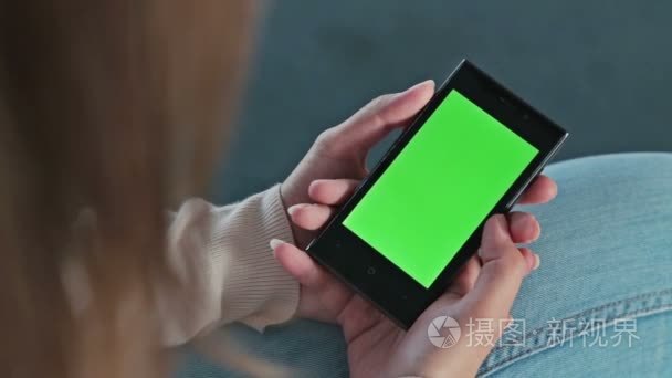 女人拿着智能手机电话与绿屏视频