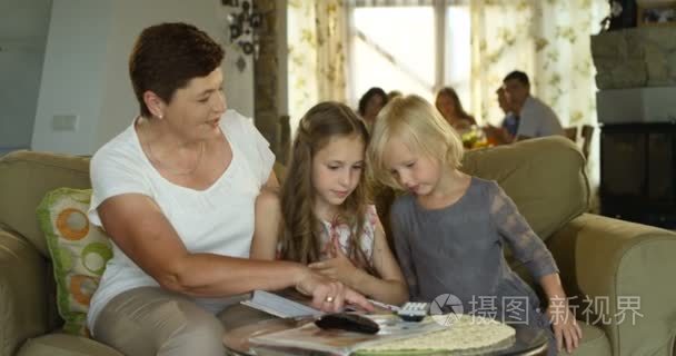 奶奶显示旧相册给她的孙女们，大家族，在餐厅背景