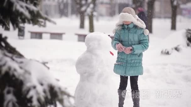 女孩造型在冬天在雪地里堆雪人视频