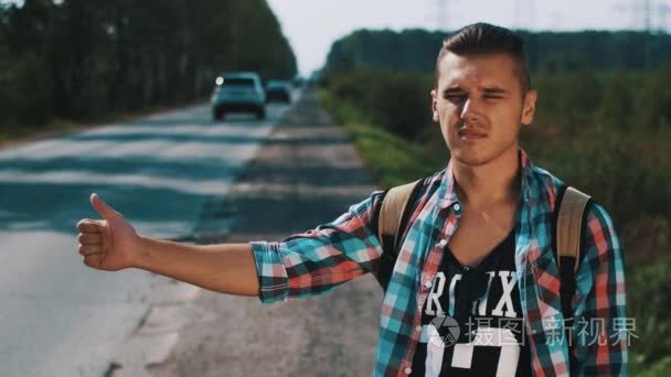 在夏季的一天在路上搭便车的年轻男孩.旅行者.大拇指.运输短视频