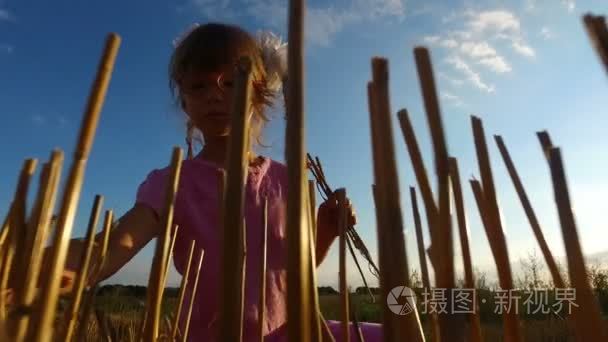 戴眼镜的女孩子在球场上收集秸秆。她带走稻草的秸秆已经收获场