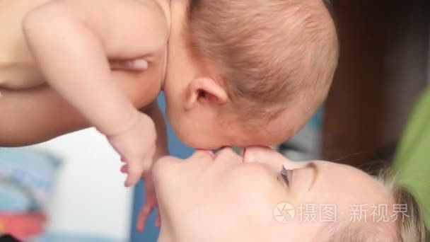 铺设的年轻母亲，上升和亲吻她可爱的宝贝男孩的特写视频