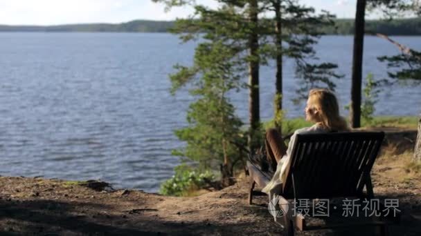 女人躺在躺椅上悬崖森林湖上