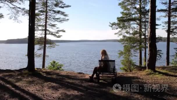 女人躺在躺椅上悬崖森林湖上
