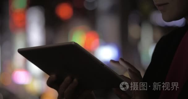 Woman with pad against colorful blurred city lights at night