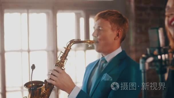 萨克斯管吹奏者蓝色西装打上金色的萨克斯管。实时性能。爵士乐
