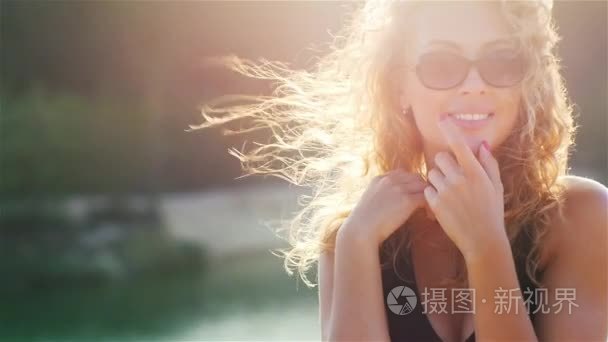 Sexy young woman smiling at the camera  flirting. The sun is shi