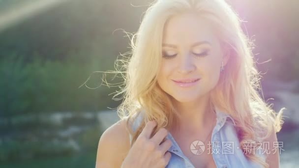 Attractive blonde smiling at the camera  close-up. Sunny day at 