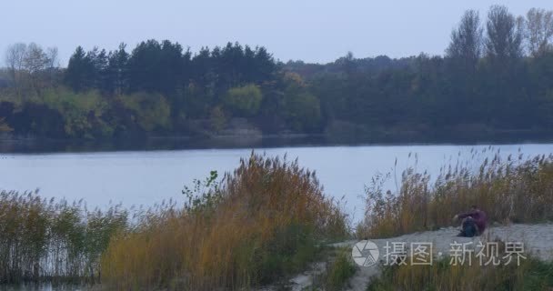 旅游背包走过河银行景观看在接在一个黄昏的绿色和黄色的草藤水和树木生长光滑水秋