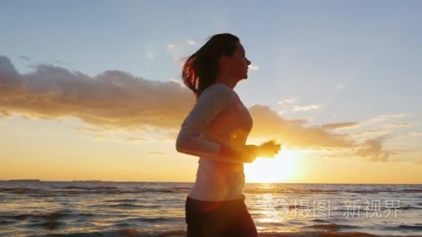 Young woman with a beautiful figure running on the beach at suns