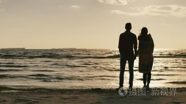 Silhouettes of young couple admiring the sunset on the sea  embr