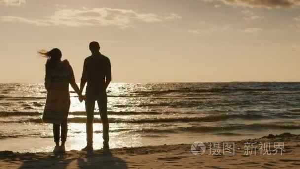 Couple in love looking at the sunset over the sea  holding hands