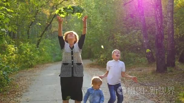 妇女带着孩子引发起地上的落叶视频