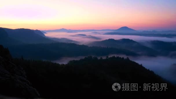 第一次太阳光线的丘陵景观冷秋天亮。山峰增加从橙色和粉红色的雾海。时间流逝