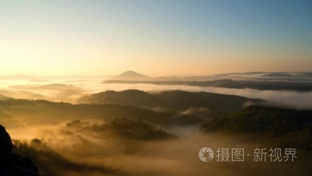 橙色寒冷的秋天破晓在丘陵景观。橙色和粉红色的雾海中谷波纹管运动平稳。时间流逝