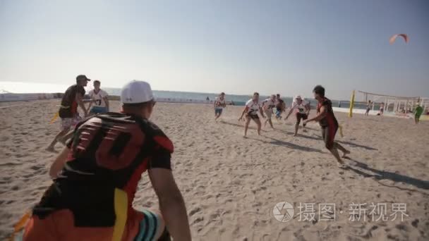 群的年轻人在一起在海边玩美式足球。沙滩运动会